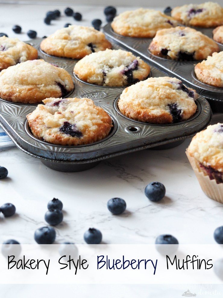 bakery style blueberry muffins in a vintage muffin tin set on white a marble background. 