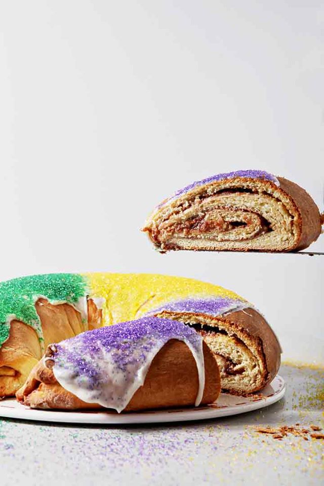 Golden ring of cream cheese and raspberry filled king cake with red, yellow, and purple sugar on top. 