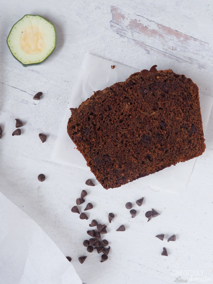A single slice of double chocolate zucchini bread surrounded with sliced zucchini and mini chocolate chips.