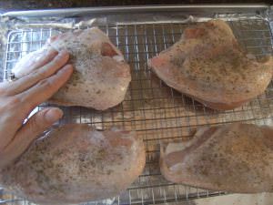 rubbing spices into bone-in chicken breasts