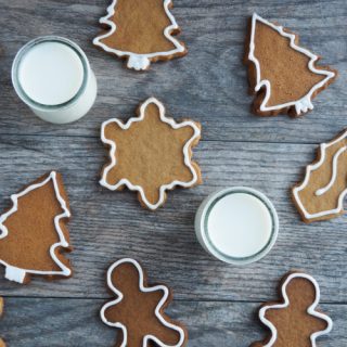 Overhead view of gingerbread cut out cookies with two glasses of milk.