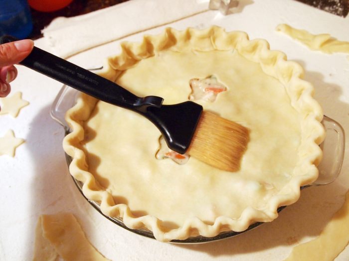 applying egg wash to the crust of a chicken pot pie