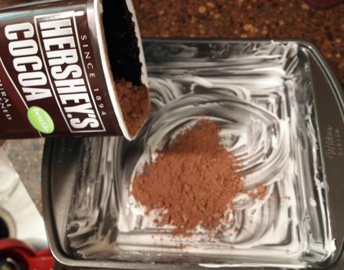 greasing a cake pan and dusting it with cocoa powder