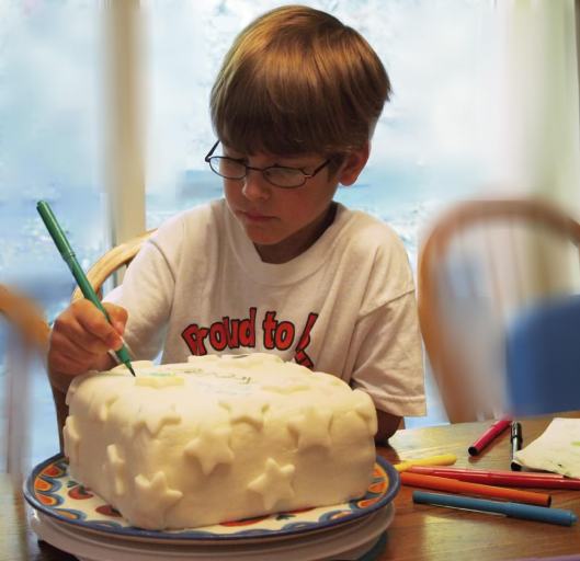 Young boy decorating a cake with fondant