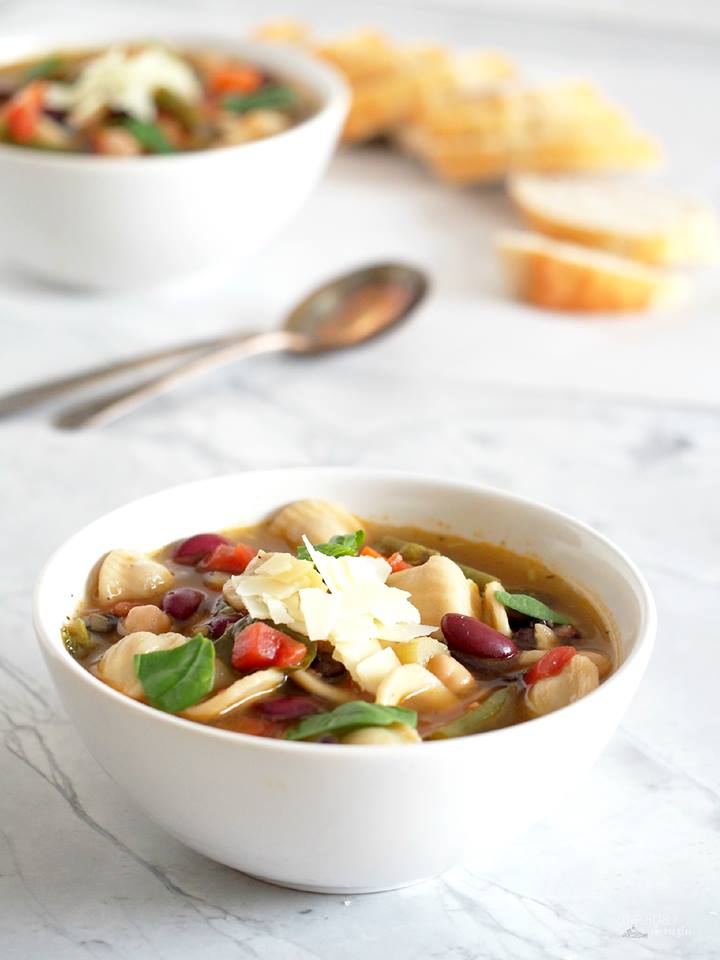 two-bowls-of-minetrone-garnished-with-shaved-parmesan-cheese