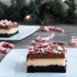 Several layered peppermint cheesecake brownies with candy canes scattered about.