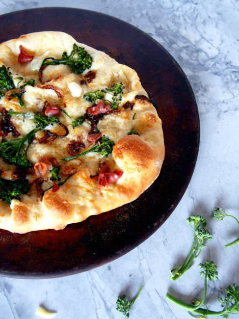 Prosciutto Broccolini Pizza proves that simple pizzeria style pizza is easily made at home! The chewy, thin crust pizza dough brushed with garlic butter, then topping it salty prosciutto, earthy broccolini, sweet caramelized onions, and shaved Asiago cheese is a taste to behold.